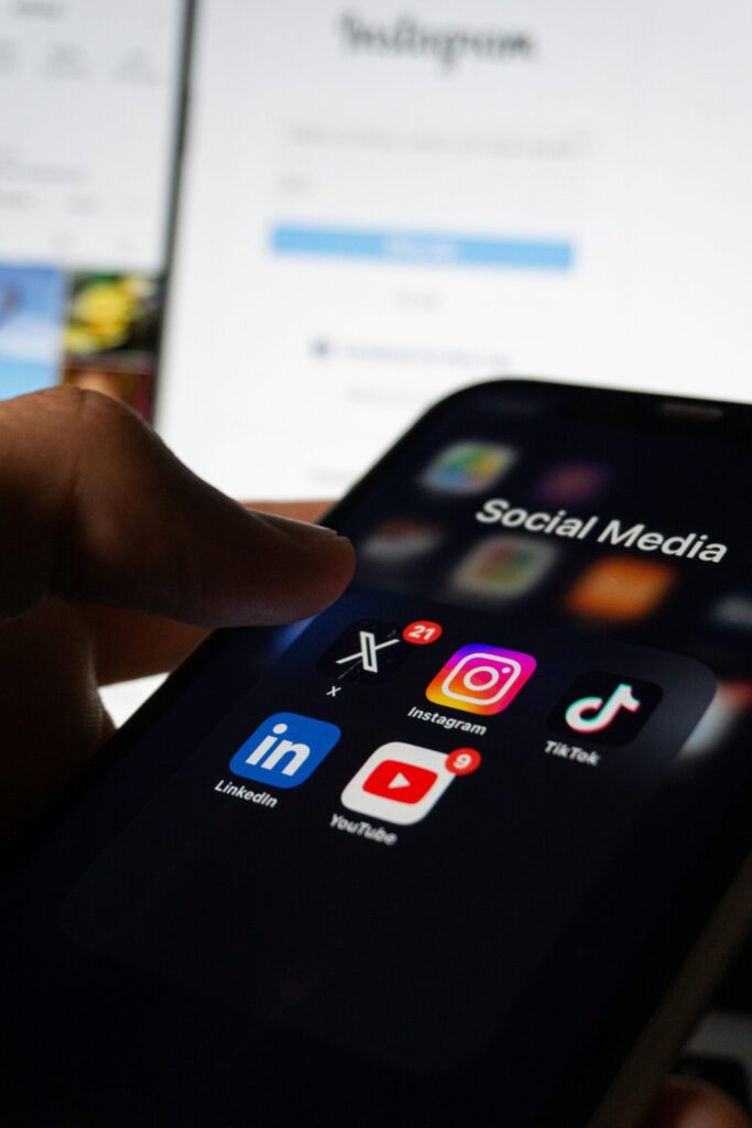 A person holding a smartphone with social media icons on the screen